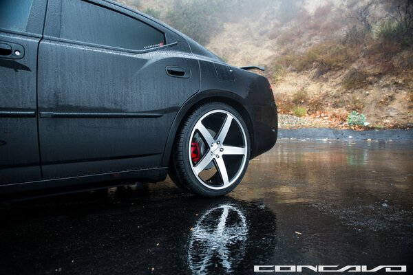 A black car of matte color against the background of cloudy weather