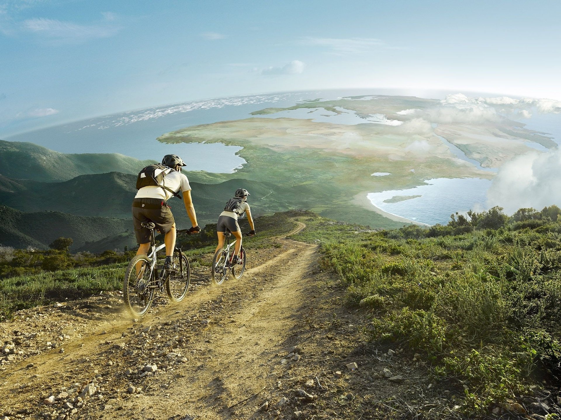 mountain bikes panorama view the sky cyclists the descent planet the ocean the highlands grass road cloud