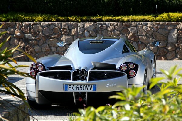 A silver car on the road. Green grass