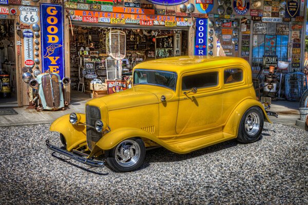 An old, yellow car is at a gas station