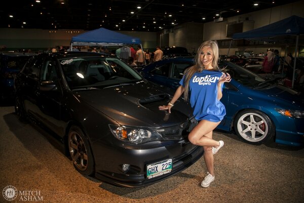 Asian woman in a blue outfit near Subaru