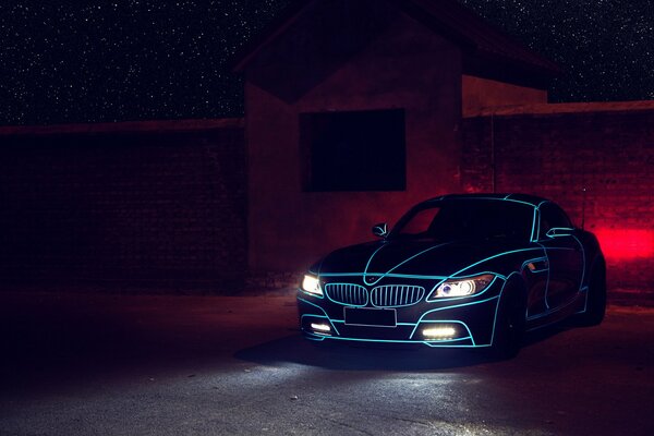 Black bmw z4 with blue backlight and headlights on at night