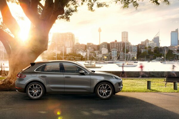 A silver Porsche Macan S parked on the embankment against the backdrop of high-rise buildings