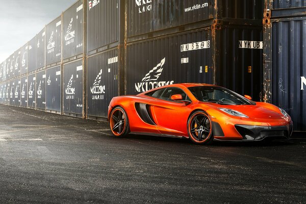 The orange mclaren mp4 -vx stands at the sea coatainers