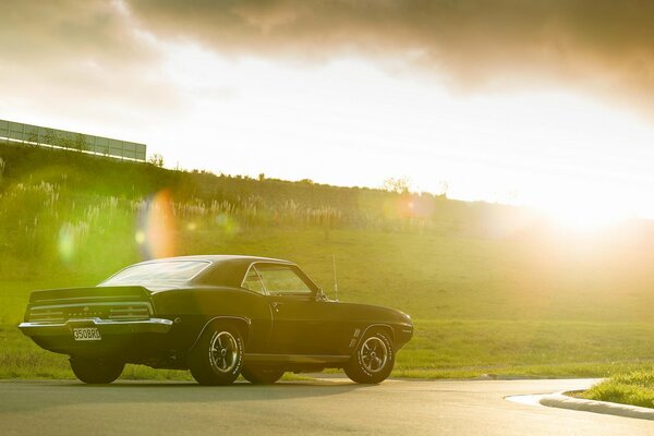 Pontiac noir se dresse sur la route sur fond de coucher de soleil