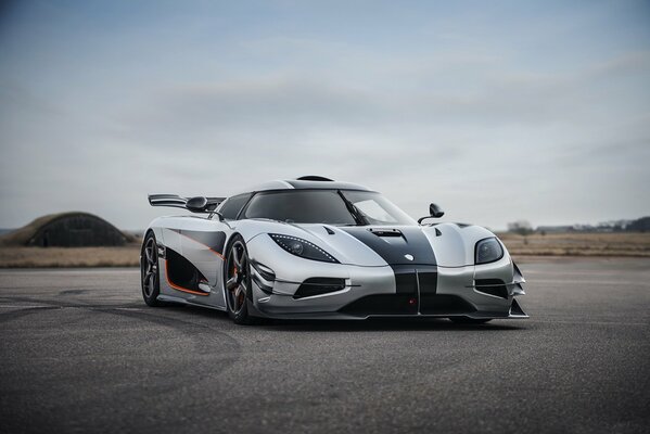 Gray sports car on the highway against the background of a hangar