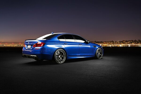 Ein blauer Bmw. Eine Nachtstadt am Horizont