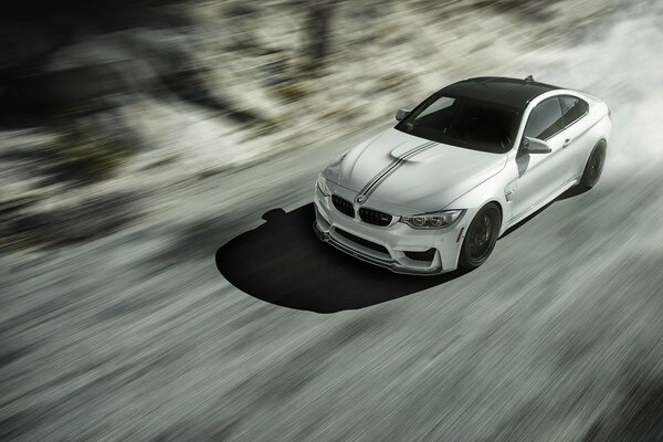 White bmw m4 driving at speed on the road