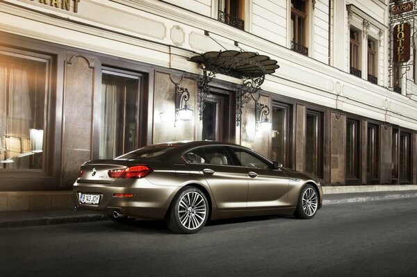 Vehículo marca BMW color bronce estacionado frente al edificio