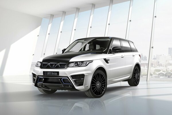 Srebrny Range Rover larte na tle ogromnych okien kolumny samochodowej