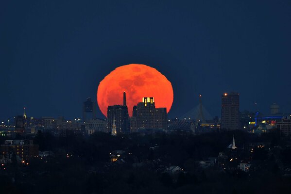 The lights of the night city on the background of a huge blood-red moon