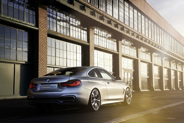 Vehículo gris marca BMW estacionado cerca del edificio de producción