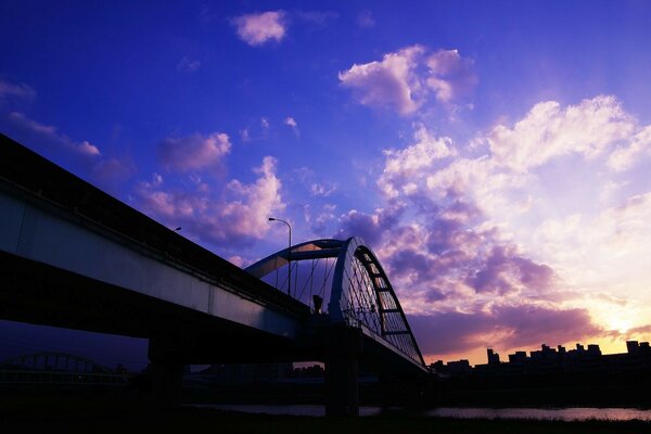 Pont dans la ville sur la rivière au coucher du soleil