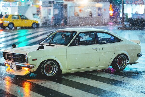 Datsun blanco bajo la lluvia en la calle