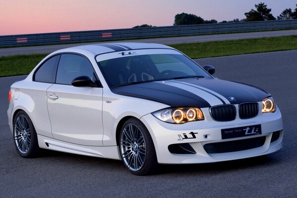 Coche de la marca BMW en la carretera durante la puesta del sol