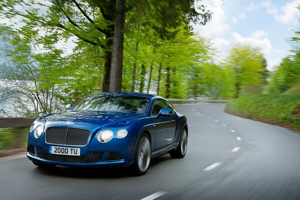 Une Bentley continental bleue roule sur une route de campagne