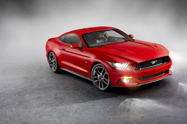 Ford Mustang rouge vif avec des phares allumés dans la fumée