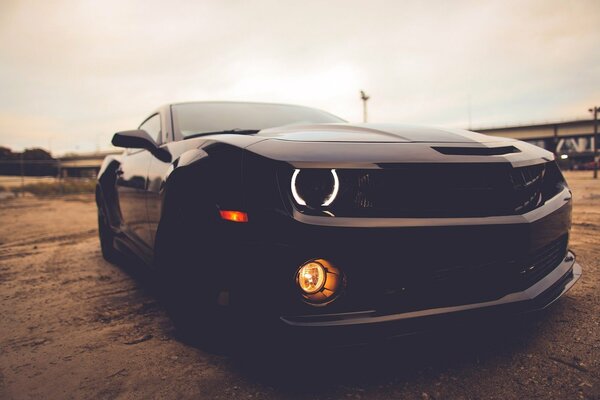 Chevrolet Camaro black, glowing headlights. Under the open sky