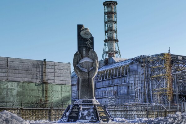 Monument on the background of a sarcophagus over the Chernobyl nuclear power plant in the danger zone