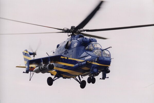 A helicopter in a yellow streak in the blue sky