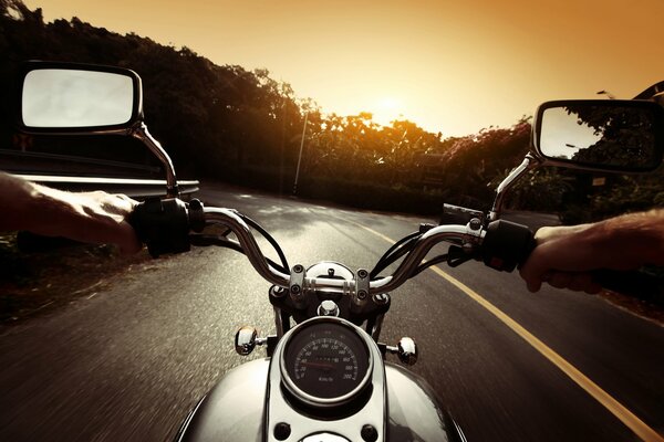 Motociclista viaja por carretera al atardecer