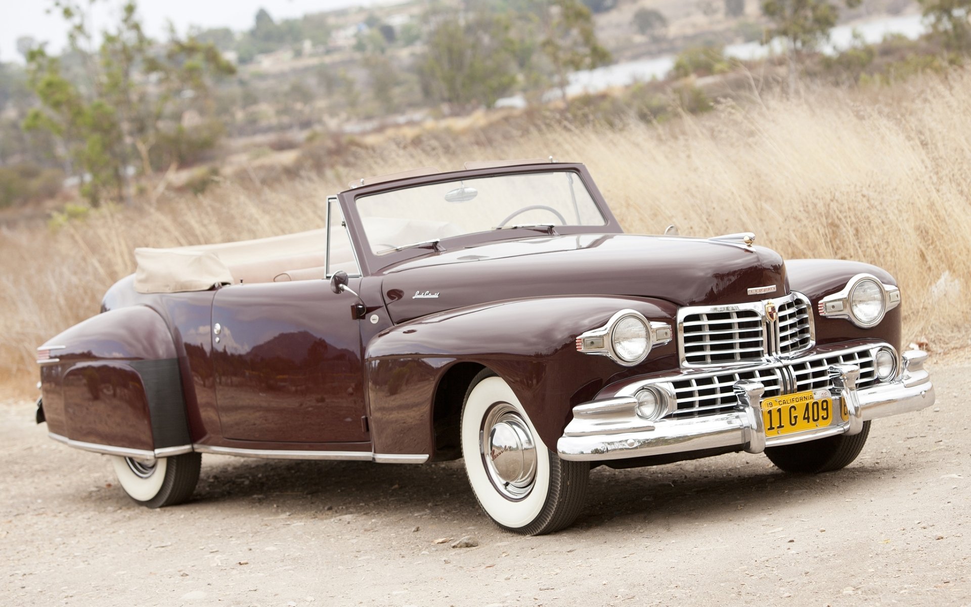 lincoln continental kabriolet 1947 lincoln.continental bordowy przód retro droga.trawa tło