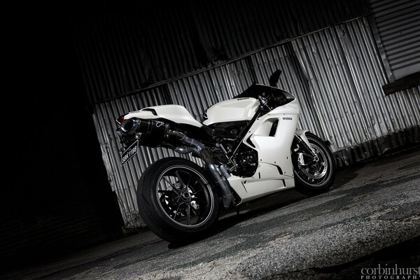 Photo en noir et blanc d une moto près d un mur de fer