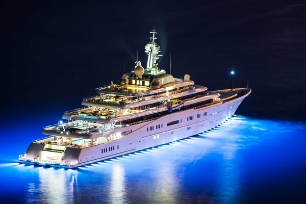 Eine coole, beleuchtete Yacht schwimmt nachts auf dem Wasser