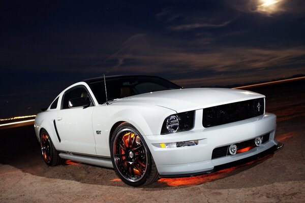 Ford Mustang blanc se tient sur la nuit