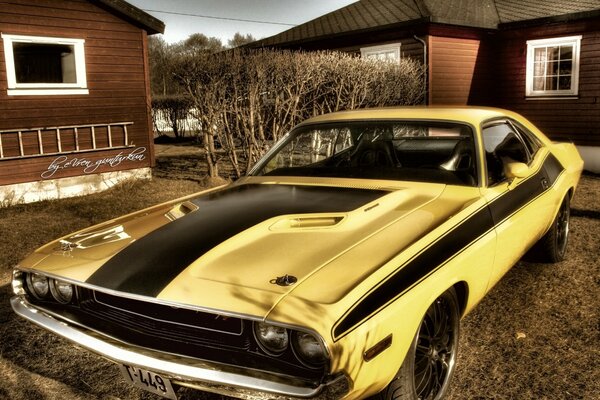 Voiture jaune Mustang dans la cour des maisons en bois