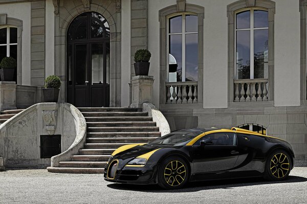 Une Bugatti noire cool avec des rayures jaunes s est arrêtée devant un luxueux manoir blanc