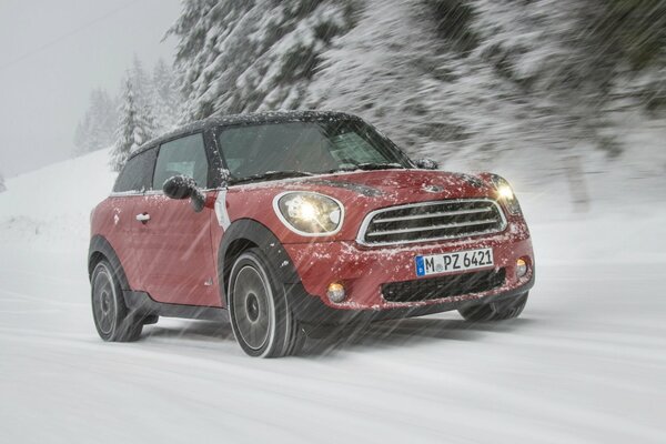 Mini cooper on a snowy highway in the woods