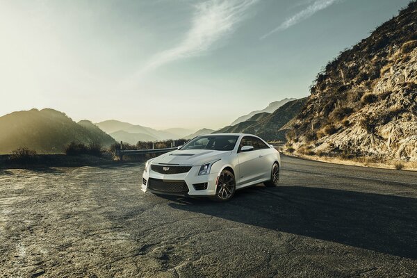 Cadillac купе белого цвета на фоне горных массивов