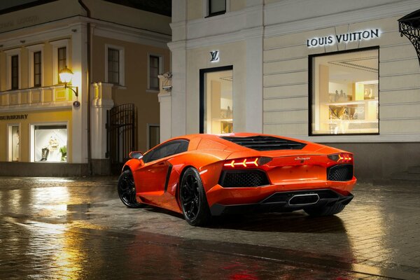 Lamborghini arancione rallentato fuori dalla boutique