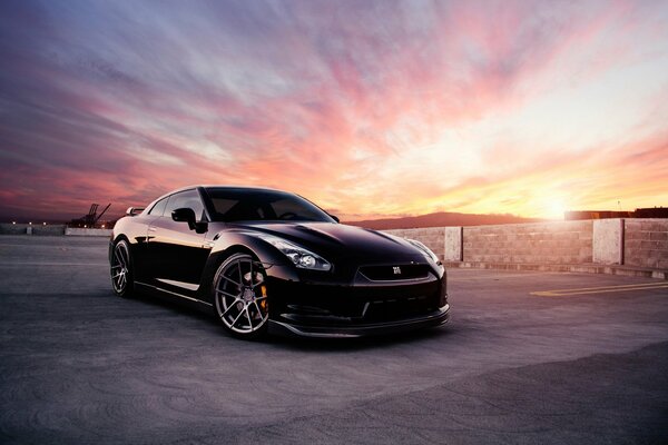 Coche Nissan negro en el fondo de una hermosa puesta de sol