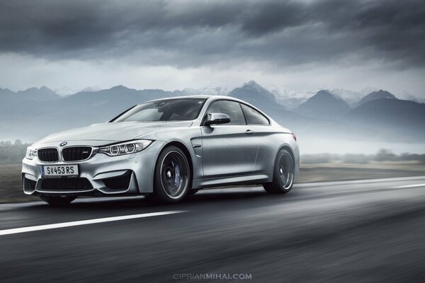 Una BMW d argento nella nebbia corre lungo la strada