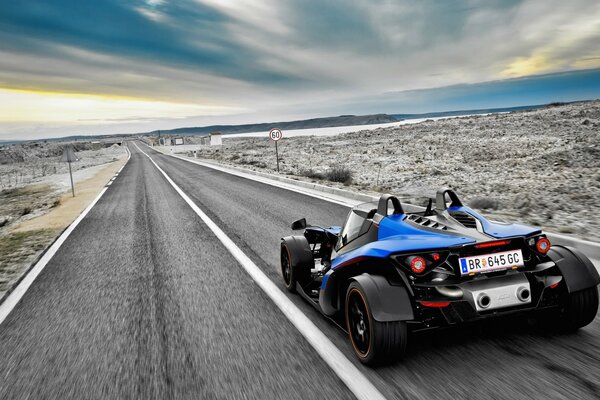 A sporty blue car drives along the road