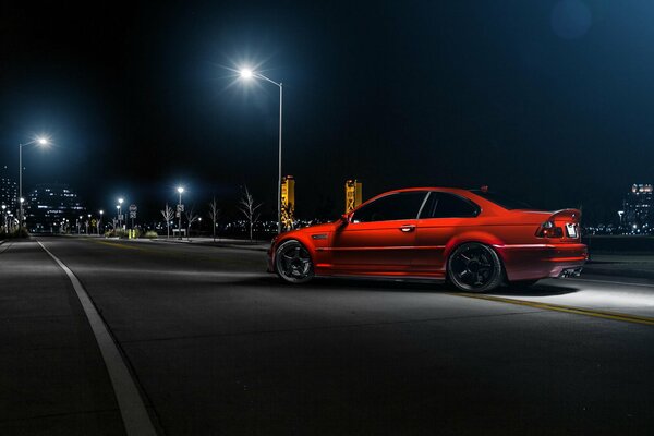 A red bmw is flying down a night street