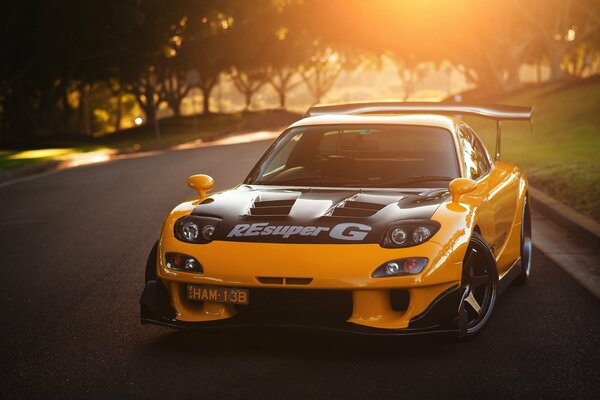 Yellow Mazda on the road in the setting sun