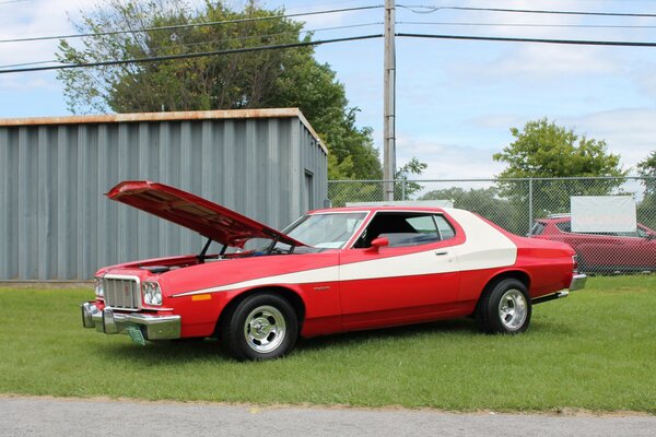 Ford rouge avec une bande blanche sur la carrosserie avec le capot ouvert