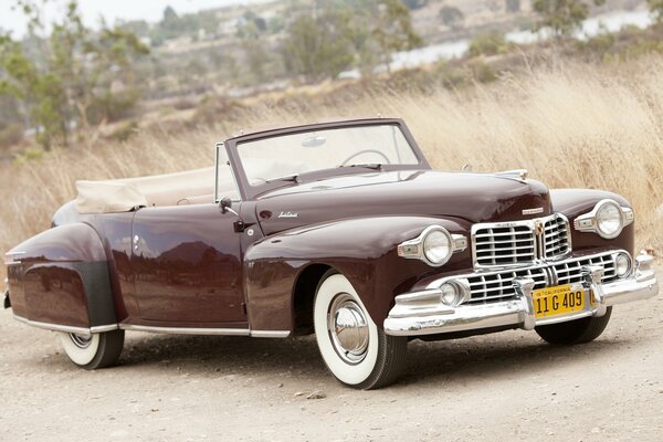 Burgunder Lincoln. continental 1947 auf hohem Gras Hintergrund