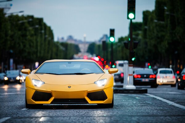 Lamborghini jaune vue de face, avec les phares allumés sur la route