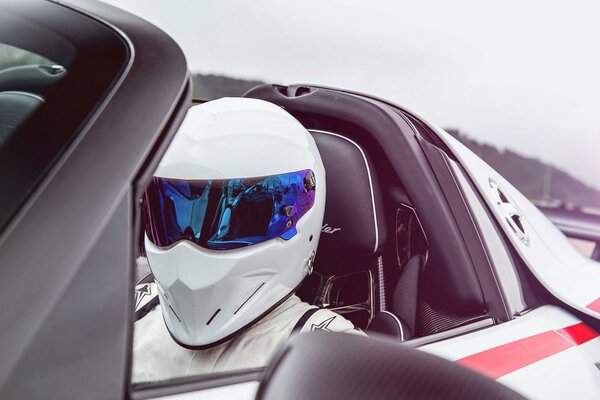 Coureur en casque dans une Porsche blanche