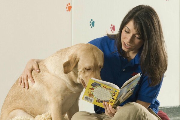 Una ragazza legge un libro al suo Retriever