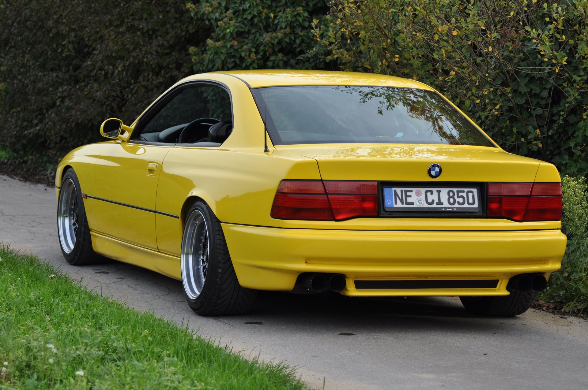 bmw 850 ci e31 bmw bmw coupe samochód sportowy żółty styl design hightech techno niemcy bawaria auto żółte auto samochód samochód transport trawa żywopłot zieleń widok z tyłu liście samochody pojazd