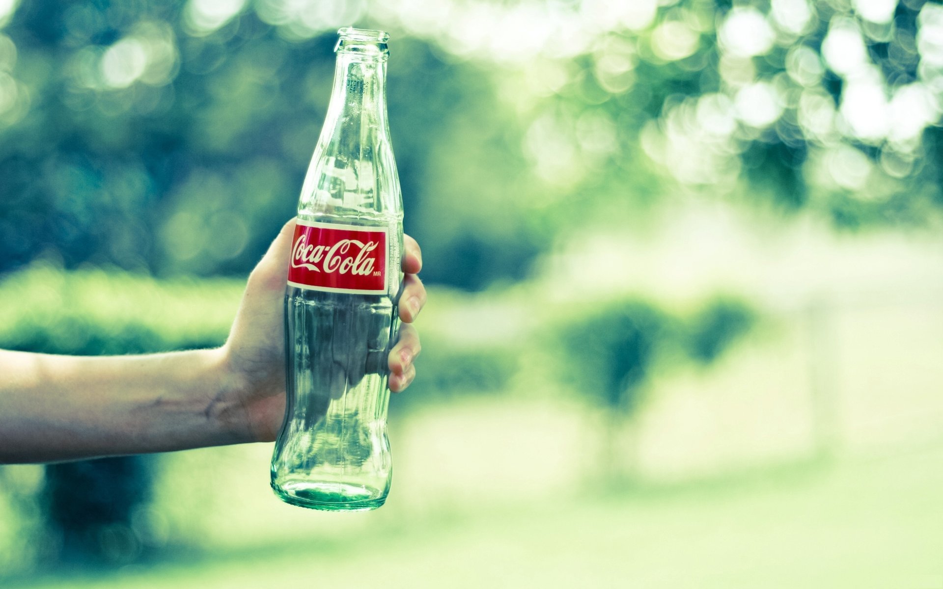 bottiglia vuota cuoco ket coca cola marca vetro mano verde bottiglia cola bevanda pubblicità sfocatura abbagliamento