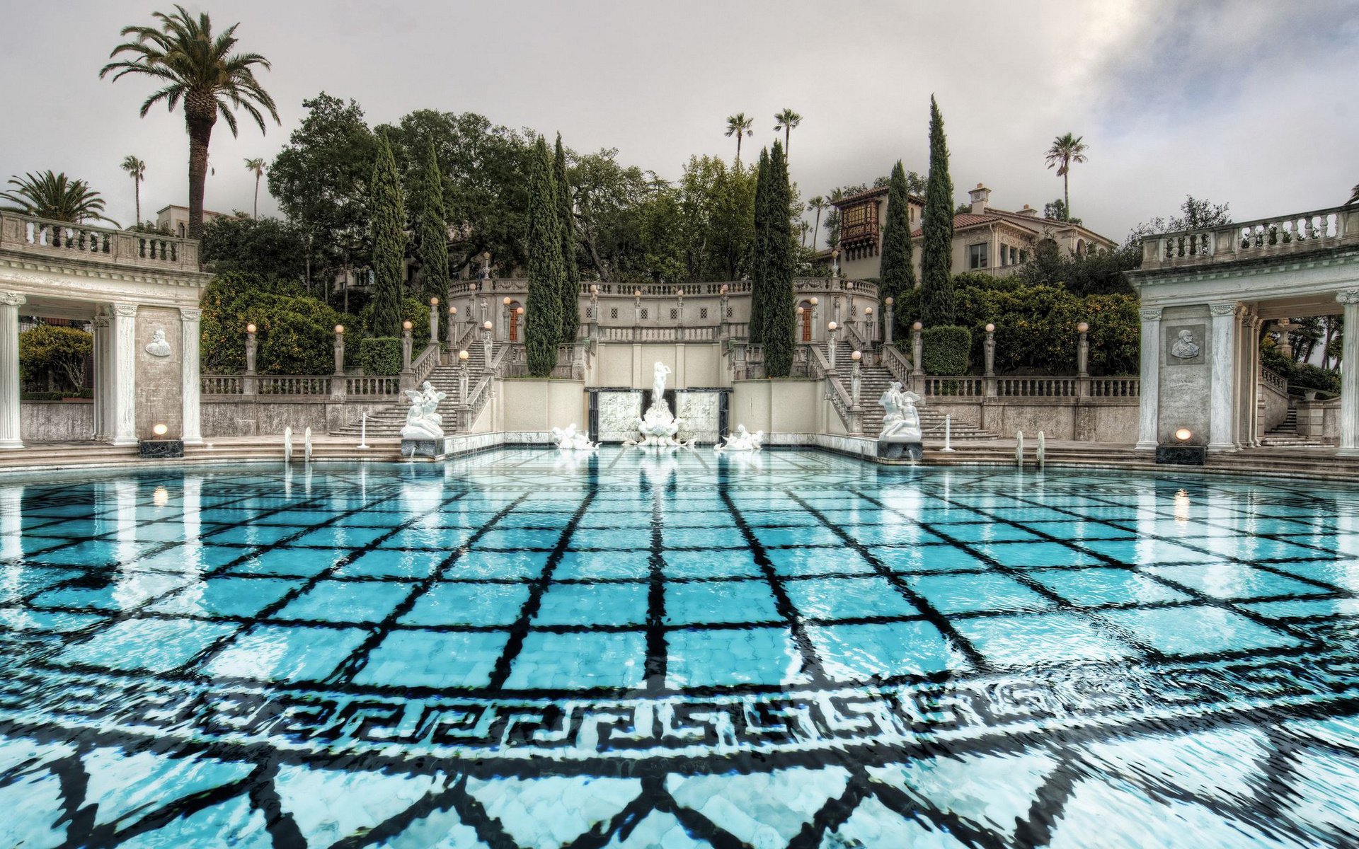 day cypress statues ladder palm trees pool water trees structure architecture steps park the sky clouds lights the bottom mansion house sculpture resort