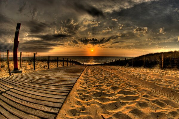 Un camino en la playa conduce a la puesta de sol en el mar