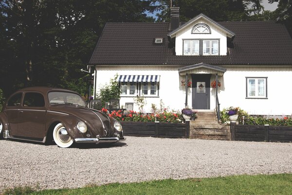 Volkwagen beetle stands in the courtyard of a one-story cottage