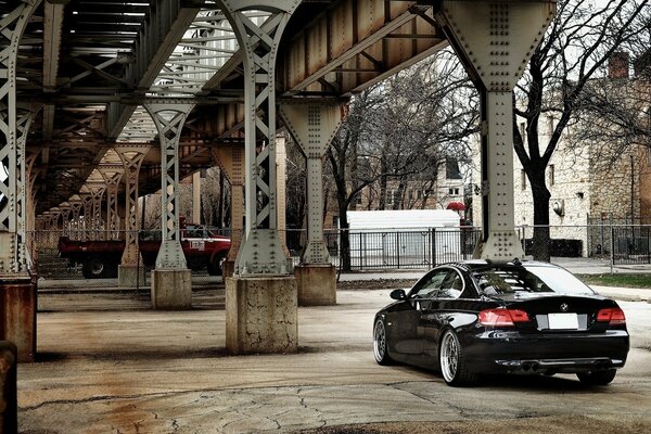 Black passenger car under the iron bridge